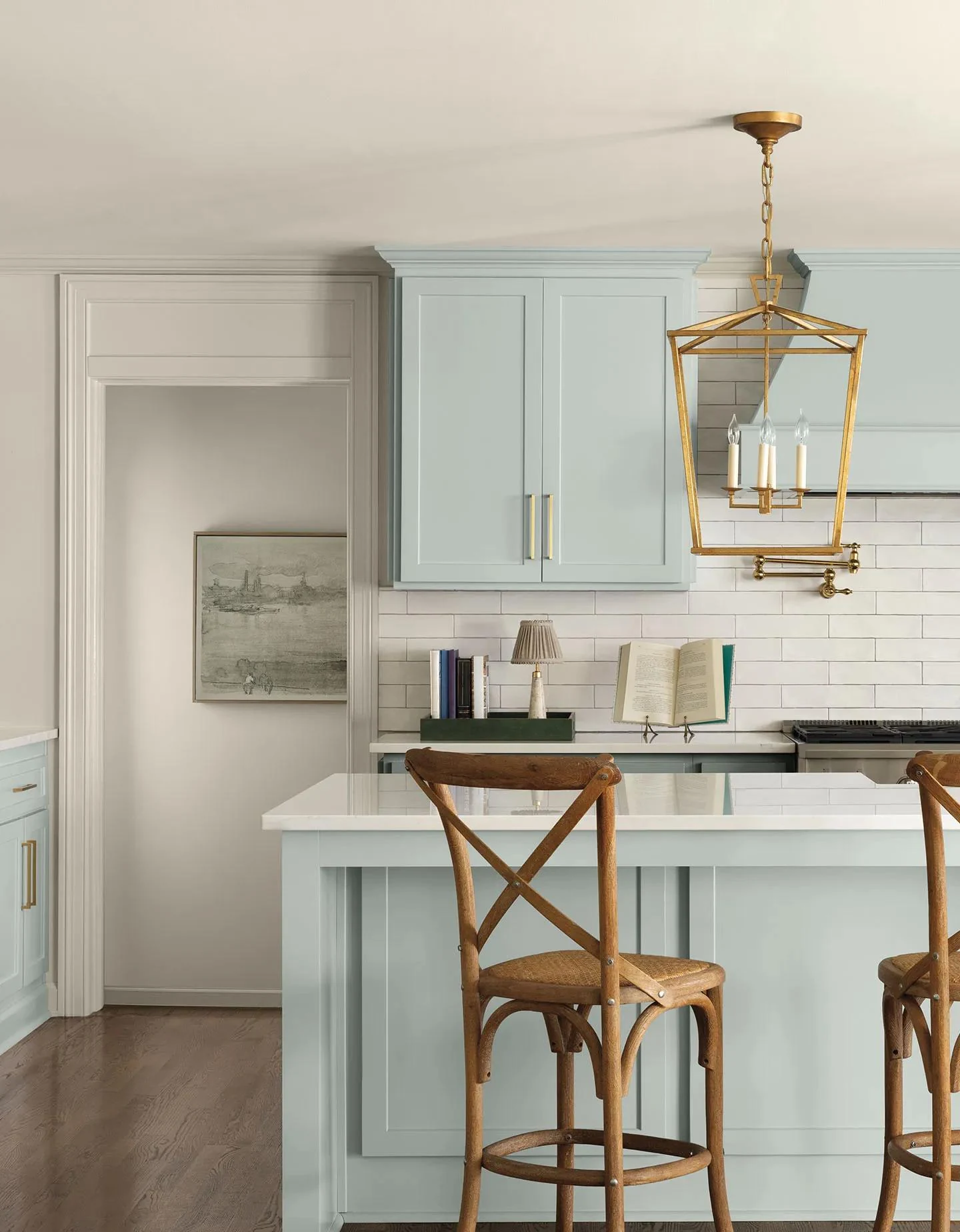 A kitchen with Nelson Blue cabinets, White Down walls, brass lighting, and a wood island top