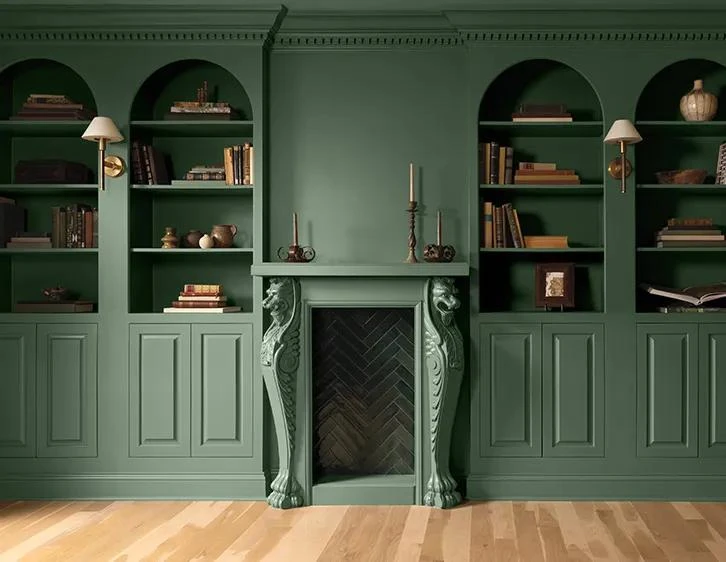 A fireplace and arched bookshelves painted in Webster Green HC-130